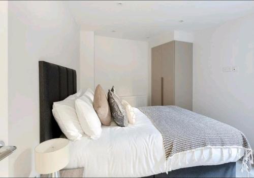 Deluxe Central London North Apartment في لندن: غرفة نوم بسرير ابيض مع مخدات بيضاء