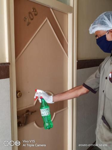 a person in a room holding a spray bottle in a door at Hotel Vaishali in Nashik