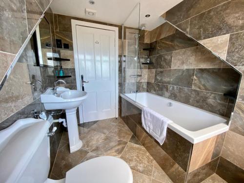 a bathroom with a tub and a sink and a toilet at Bridgemill in Girvan
