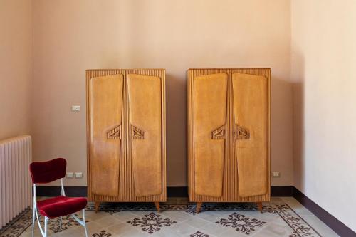 two wooden cabinets in a room with a red chair at Distilia Dimora Salentina in San Cesario di Lecce