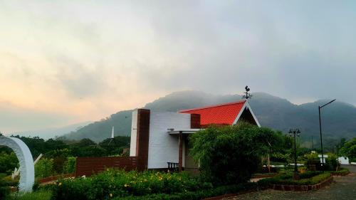 a building with a red roof with a mountain in the background at Nostravila in Lonavala