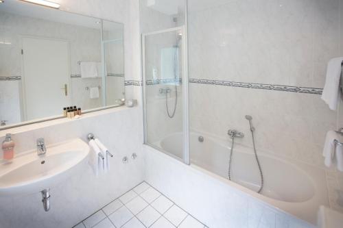 a white bathroom with a sink and a shower at Bad Emser Hof in Bad Ems