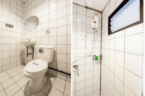 a white bathroom with a toilet and a mirror at Gfeel Hostel in Bangkok