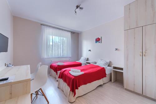 two beds in a white room with a desk and a table at Pensjon Polska in Poznań