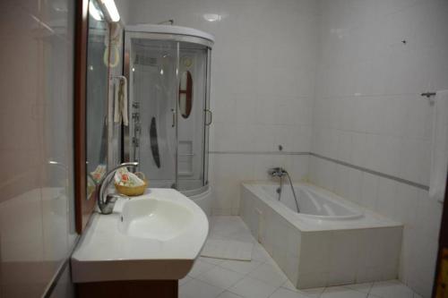 a bathroom with a shower and a sink and a tub at New Charity Hotel International in Arusha