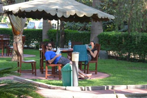 two people sitting at a table under an umbrella at New Charity Hotel International in Arusha