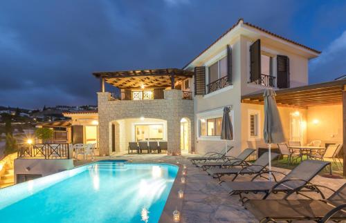 a villa with a swimming pool in front of a house at Resitour - Perneri Four Bedroom Villa in Paphos