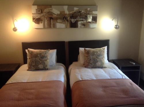 two beds in a room with lights on the wall at Jock of the Bushveld in Barberton
