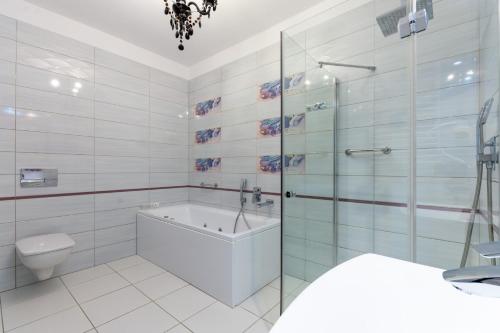 ダルウフコにあるHotel Janのバスルーム(バスタブ、トイレ、ガラス張りのシャワー付)
