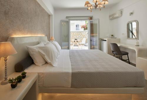 a bedroom with a white bed and a desk at Blue Sea Hotel in Kamari