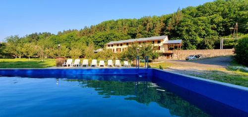 a swimming pool with chairs in front of a house at Restland Dilijan Family Hotel in Dilijan