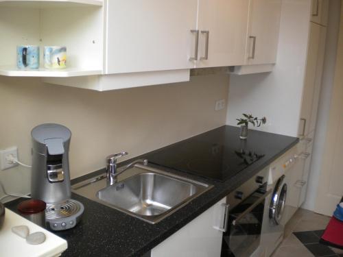 a kitchen with a sink and white cabinets at Bed & Breakfast Maria in Rotterdam