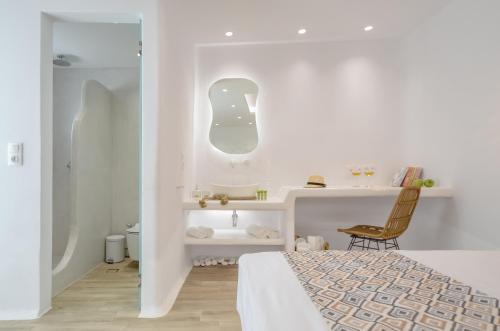 a white bedroom with a bed and a desk at Naxian Spirit Inn in Naxos Chora
