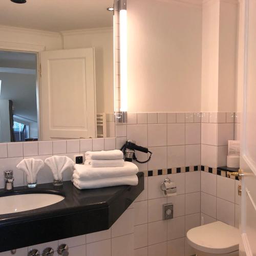 a bathroom with a sink and a toilet and towels at Hotel Scherf Residenz in Bad Lippspringe
