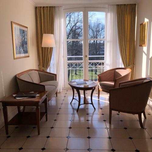 a living room with chairs and a table and a window at Hotel Scherf Residenz in Bad Lippspringe