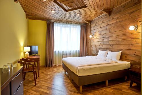 1 dormitorio con 1 cama y pared de madera en Фальварак KUPALA, en Senitsa