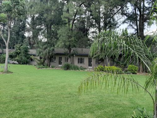 a house in a yard with a green lawn at Wayside Lodge in Waterval Boven