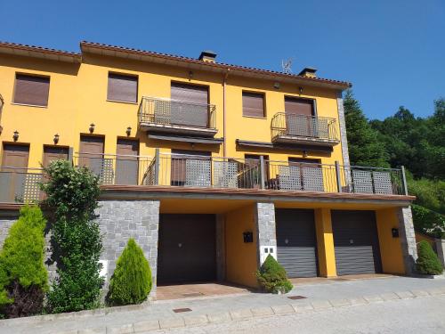 a yellow apartment building with balconies and bushes at Apartament FRESER II in Ribes de Freser