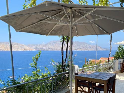 a table with an umbrella on a balcony overlooking the water at Thodoris Infinity View Apartments in Symi