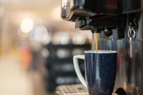 a coffee is being poured into a coffee cup at Holiday Inn - the niu, Coin Frankfurt Ostend by IHG in Frankfurt/Main