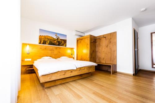 Schlafzimmer mit einem großen Bett mit einem Kopfteil aus Holz in der Unterkunft Hotel zur Post in Heilbronn
