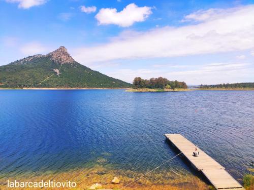 a man on a dock in a lake with a mountain at Alojamientos rurales La Barca del tío Vito in Peloche