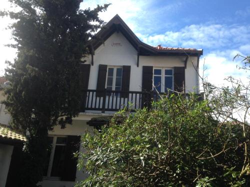 a white house with black windows and a balcony at Villa des T Studio in Arcachon