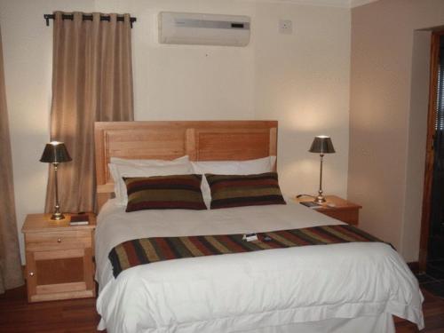 1 dormitorio con 1 cama blanca grande y 2 lámparas en Uitsigpark Guest@home4U, en Centurion