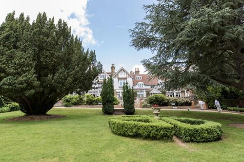 a garden with bushes and trees and a building at Rowhill Grange Hotel & Utopia Spa in Dartford