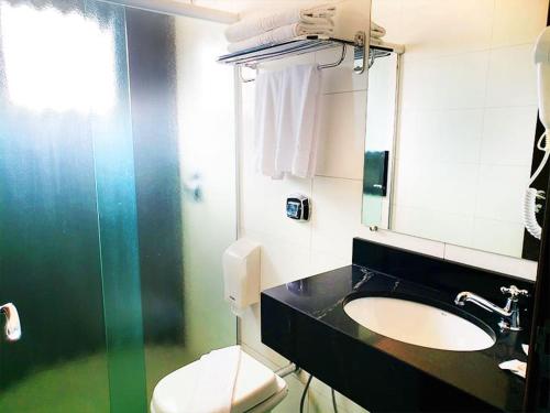 uma casa de banho com um lavatório, um WC e um espelho. em Hotel Opuka em Sorriso
