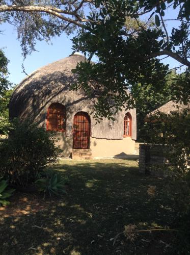 a house with a thatched roof with red windows at Jock of the Bushveld in Barberton