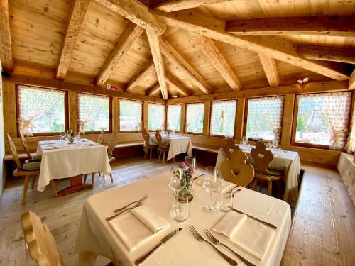 a dining room with tables and chairs and windows at Ristorante Rifugio Ospitale in Cortina dʼAmpezzo