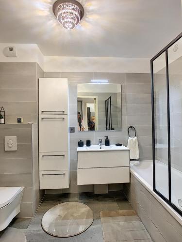 une salle de bain avec un lavabo, une baignoire et un miroir dans l'établissement Palm Beach apartment with a pool in the residence, à Cannes