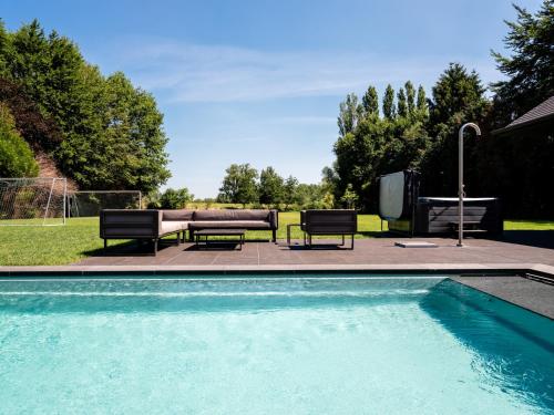 a swimming pool with two chairs and a couch at B&B Welness Sport and Pleasure in Laarne