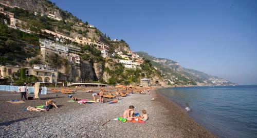 a group of people laying on a beach near the water at La Caravella di Positano - Relais, Beach & Residences in Positano