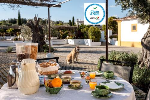 Um cão atrás de uma mesa com comida. em Quinta Da Espada em Évora