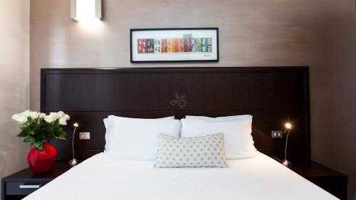 a bed with white pillows and a picture on the wall at Hotel Lis in Asti