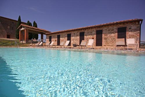 una grande piscina con sedie e un edificio di Agriturismo Casale Dello Sparviero a Castellina in Chianti