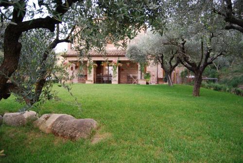a brick house with a yard with grass and trees at Bed and Breakfast La casa delle rondini in Staffolo