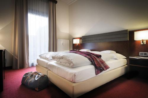 ein Hotelzimmer mit einem großen Bett mit weißer Bettwäsche in der Unterkunft Hotel de France Wiesbaden City in Wiesbaden