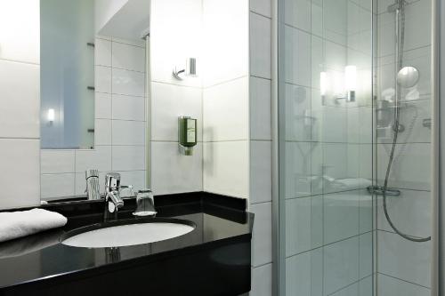 a bathroom with a sink and a shower at Hotel de France Wiesbaden City in Wiesbaden