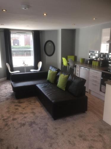 a living room with a black couch and a kitchen at Stafford apartments in Stafford