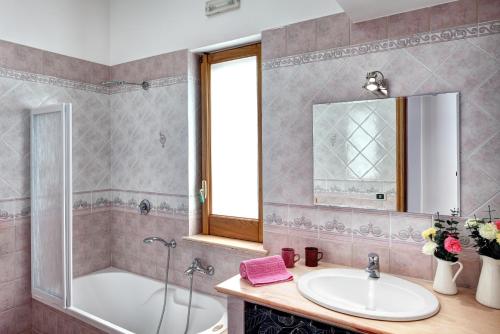 bagno con lavandino, vasca e specchio di A Taste of Sun Apartment a Sorrento