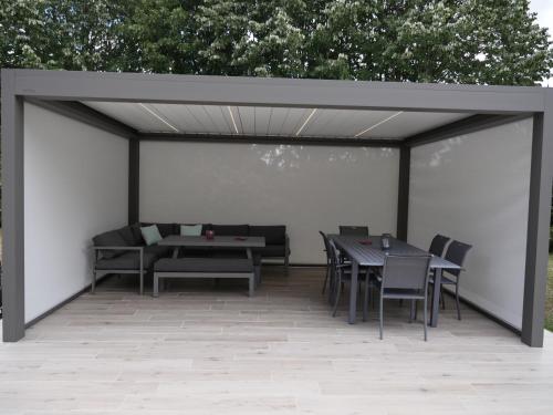 une pergola avec des tables et des chaises sur une terrasse dans l'établissement Le Manoir de Louviers, à Louviers