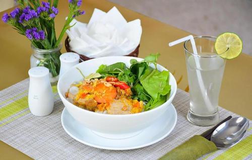 a bowl of food on a table with a salad and a glass of water at Maya Hotel 2 in Con Dao