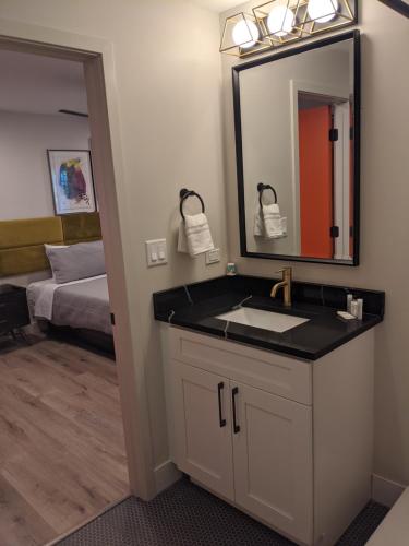 a bathroom with a sink and a mirror and a bed at 4411 Inn & Suites in Michigan City