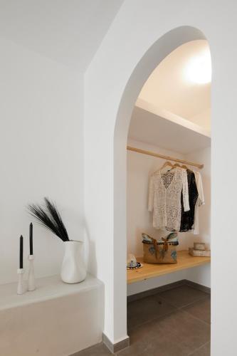 a white hallway with a shelf and an archway at Blue Sea Hotel in Kamari