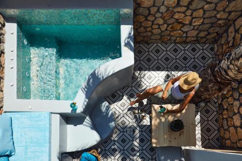 a man in a hat standing next to a swimming pool at Blue Sea Hotel in Kamari