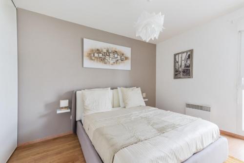 une chambre avec un grand lit avec des draps blancs dans l'établissement Appartement des Rêves Bleus - Welkeys, à Montévrain