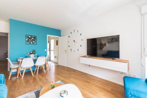 un salon avec un mur bleu et une grande télévision à écran plat dans l'établissement Appartement des Rêves Bleus - Welkeys, à Montévrain